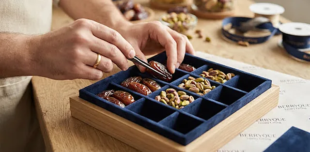 Hands arranging premium dates into a Berryque presentation tray